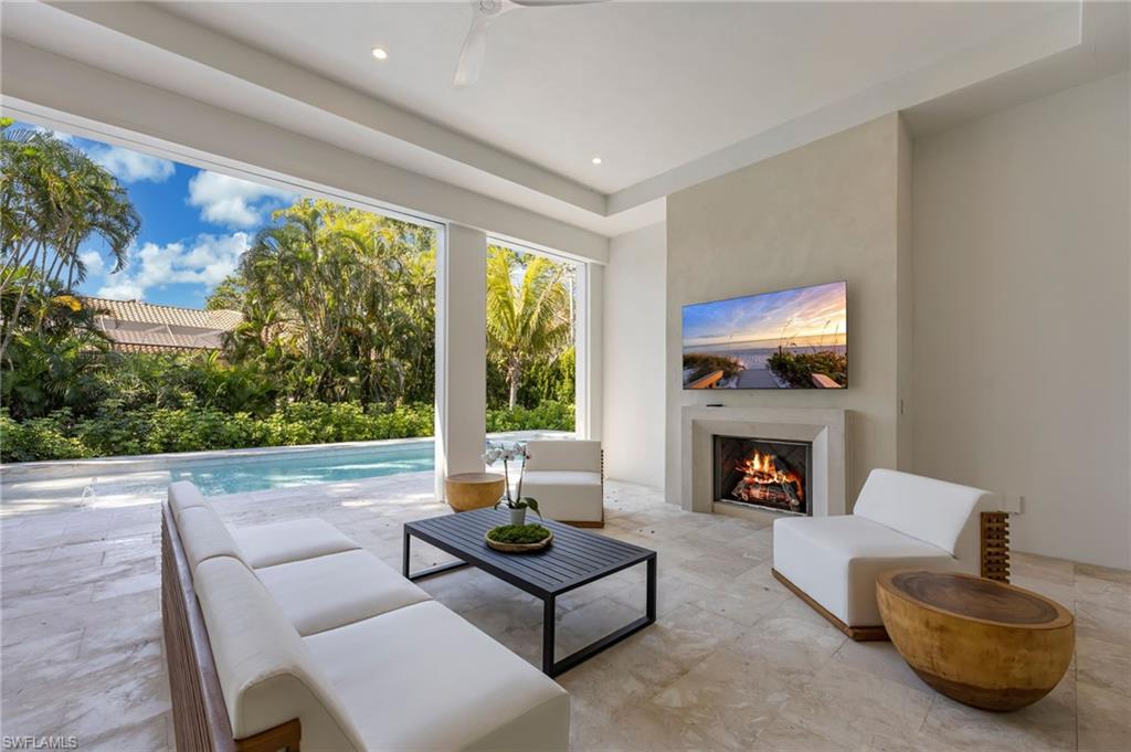 Living room with a warm lit fireplace, ceiling fan, and recessed lighting