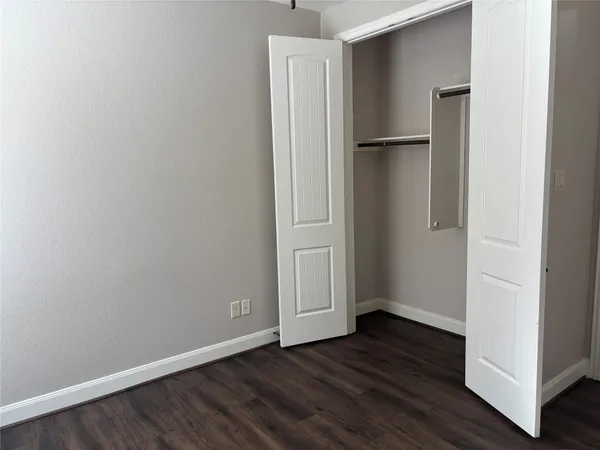 a view of an empty room with wooden floor and closet