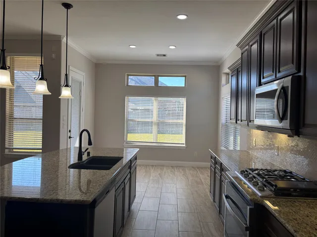 a kitchen with granite countertop stainless steel appliances a sink stove and cabinets