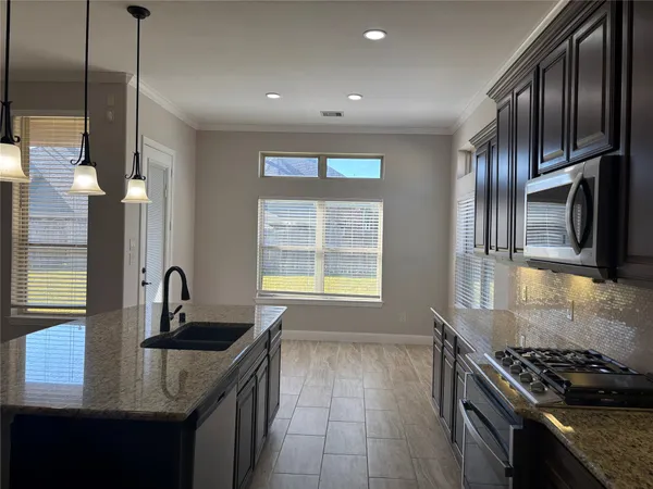 a kitchen with granite countertop stainless steel appliances a sink stove and cabinets