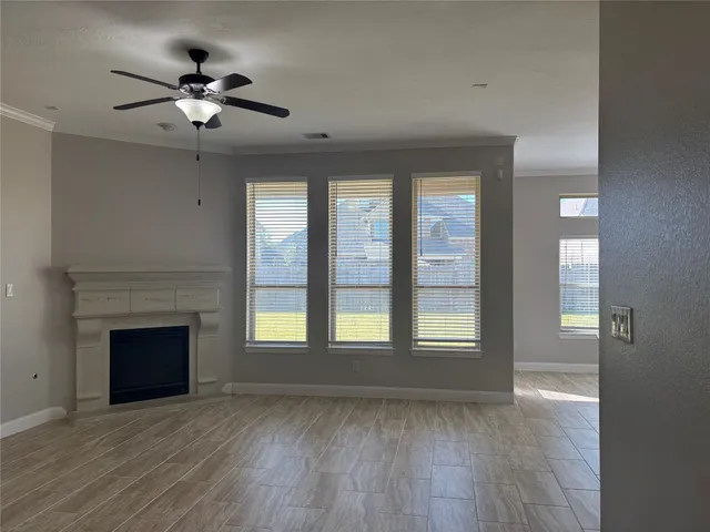 a view of an empty room with wooden floor fireplace and a window