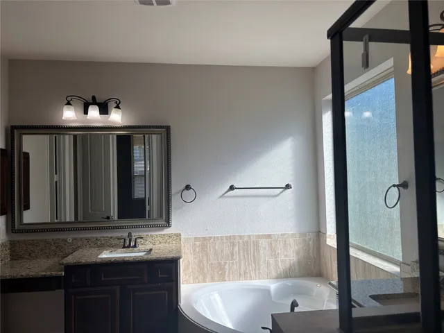 a bathroom with a granite countertop sink mirror and a bathtub