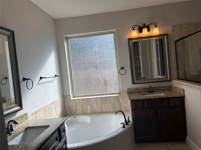 a bathroom with a tub sink and mirror
