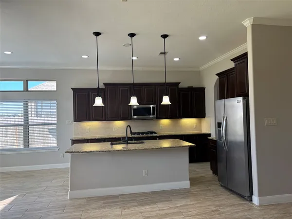 a kitchen with stainless steel appliances granite countertop a refrigerator a sink and a stove