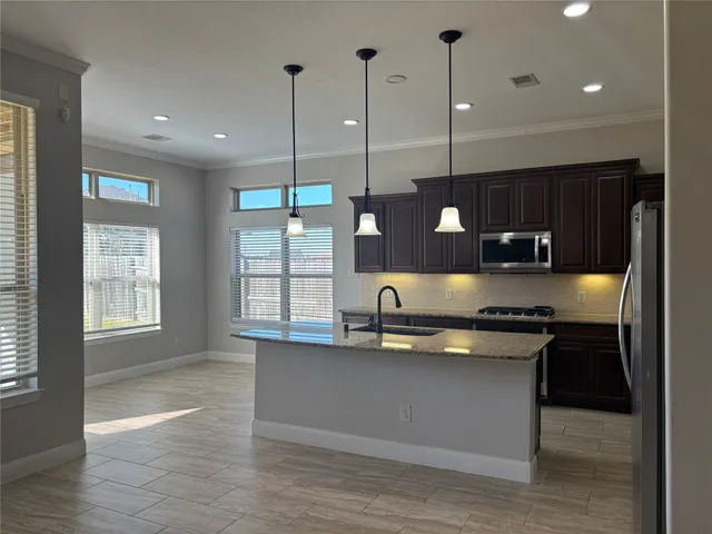 a kitchen with stainless steel appliances granite countertop a sink a stove and a wooden floors