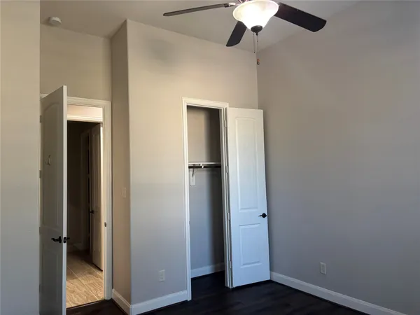 an empty room with wooden floor closet and chandelier fan