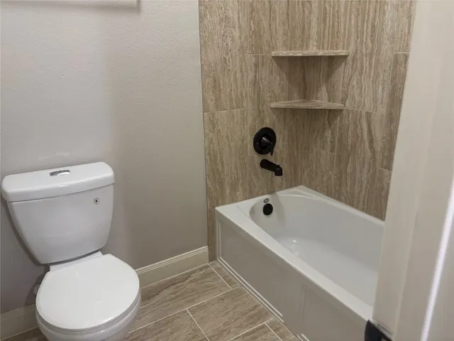 a white toilet sitting next to a bath tub