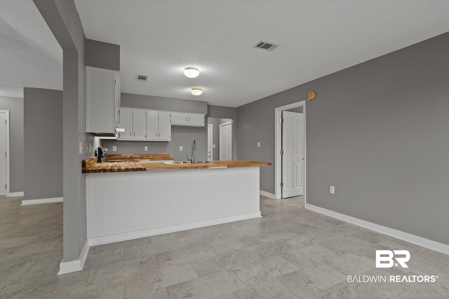 16418 Avent Lane Foley, AL 36535 - Photo 17 of 30 Kitchen with a textured ceiling, kitchen peninsula, white cabinetry, and sink