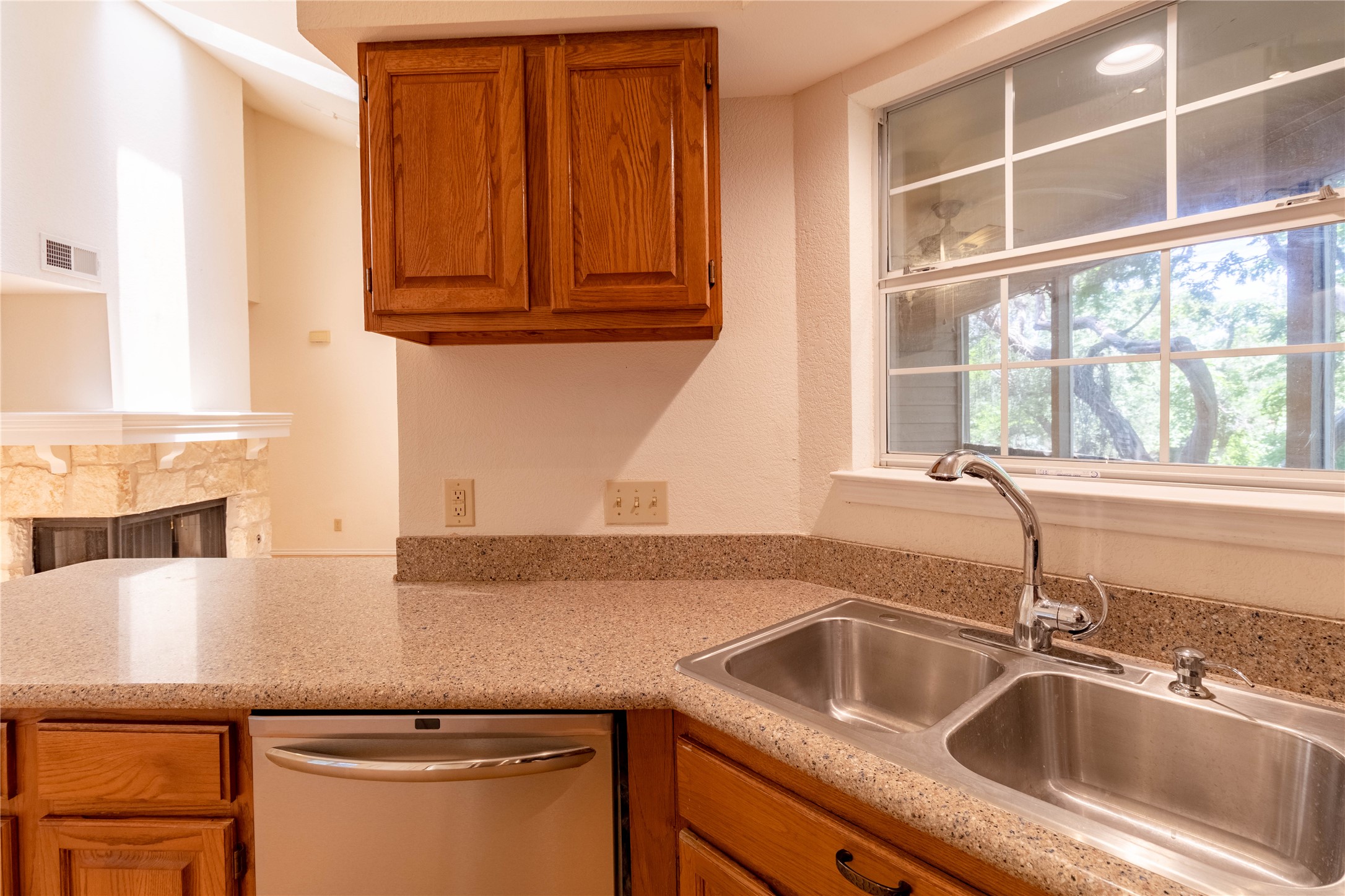 3809 Spicewood Springs Road, Unit 253 Austin, TX 78759 - Photo 11 of 23 Kitchen featuring wood finish cabinetry, dishwasher, a fireplace, and light stone countertops