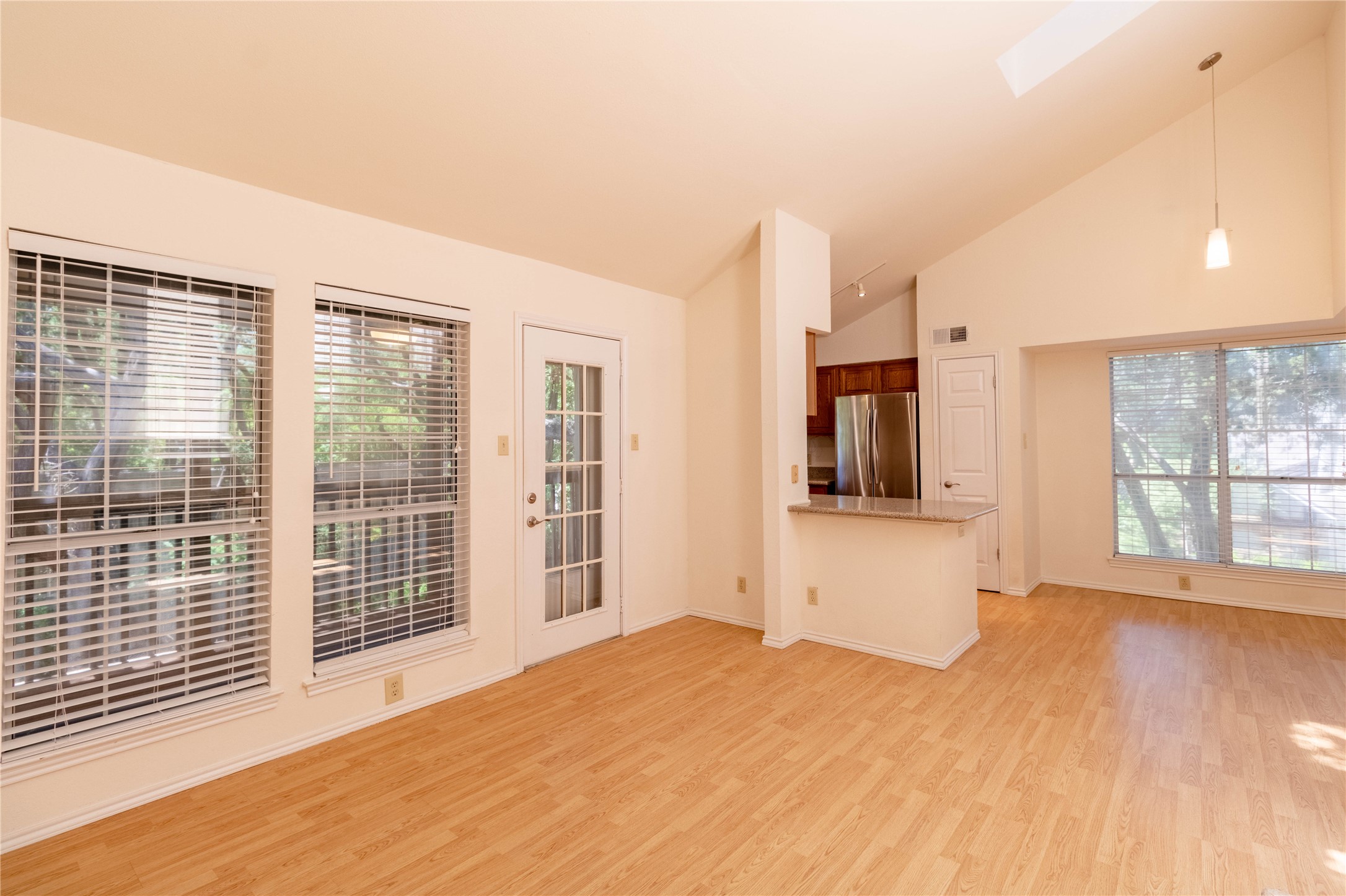 3809 Spicewood Springs Road, Unit 253 Austin, TX 78759 - Photo 6 of 23 Unfurnished living room featuring light wood-type flooring, vaulted ceiling, a skylight, and healthy amount of natural light