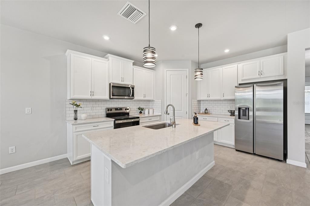 20280 Concerto Place Venice, FL 34293 - Photo 10 of 37 a kitchen with white cabinets and stainless steel appliances