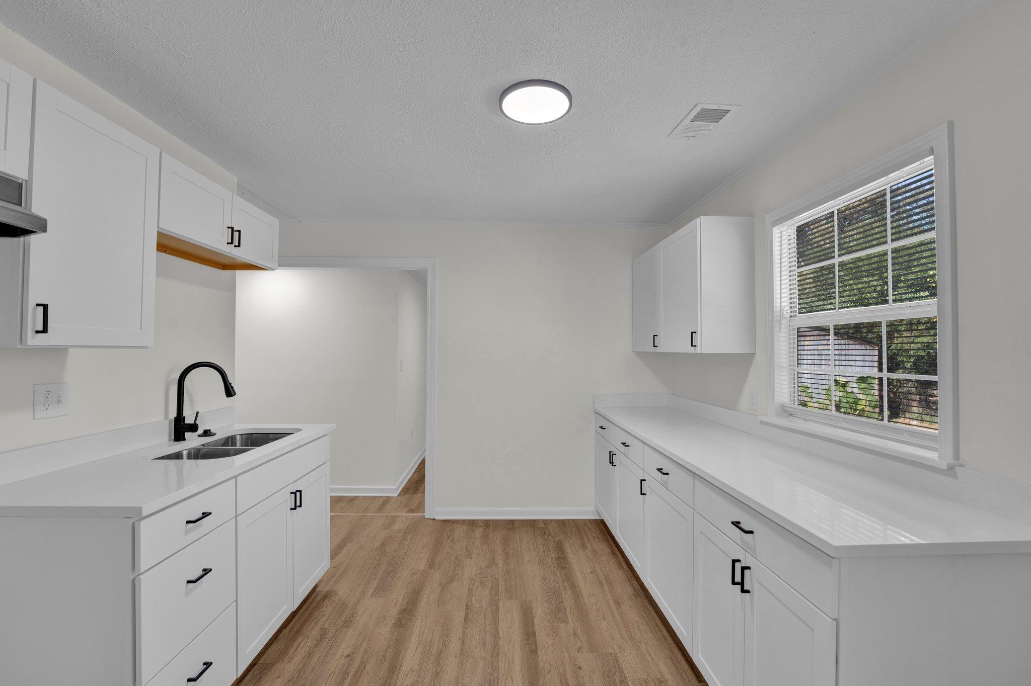 7829 Admiral Road Millington, TN 38053 - Photo 12 of 28 Kitchen featuring white cabinetry, light hardwood / wood-style flooring, a textured ceiling, and sink