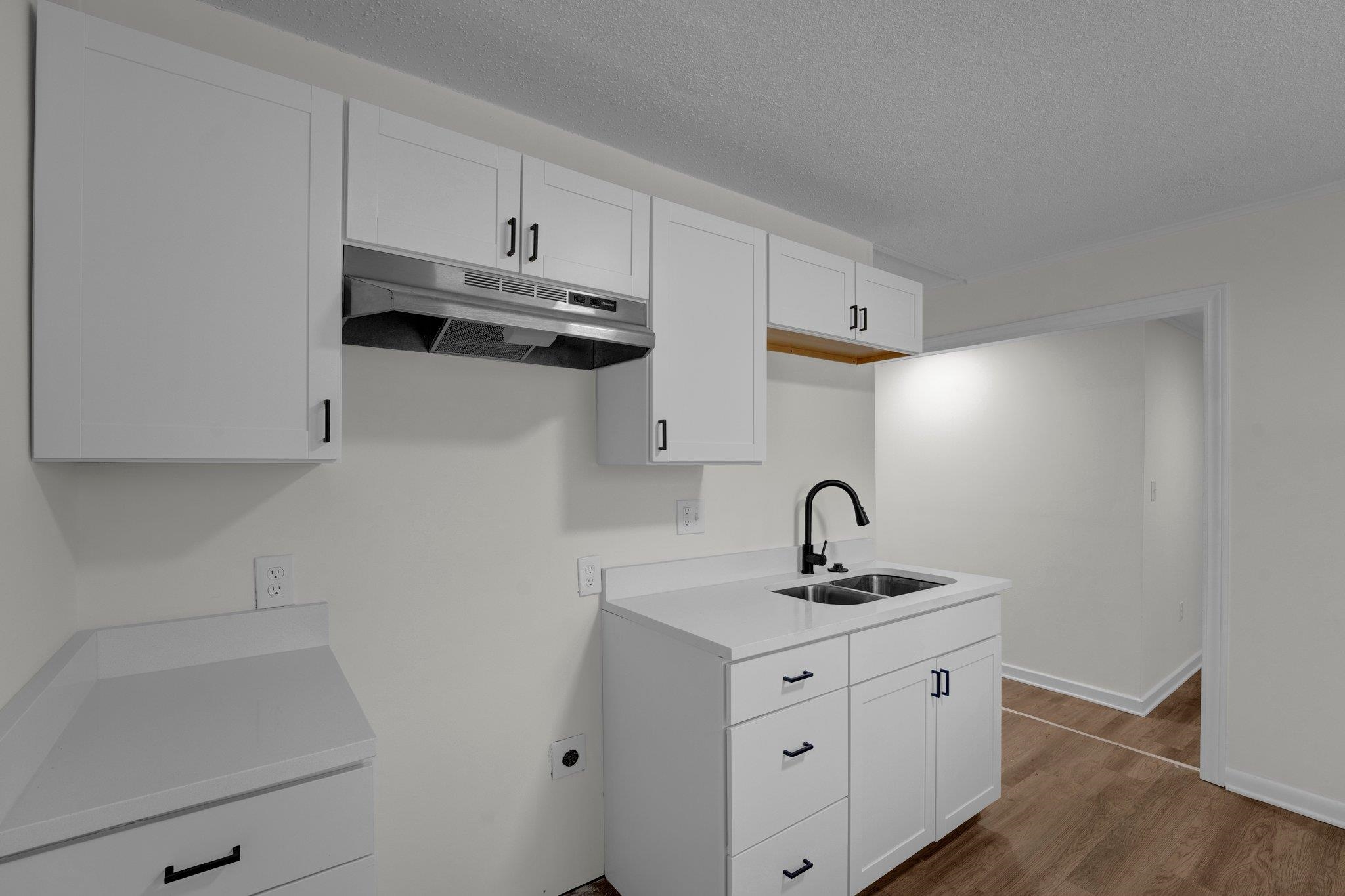 7829 Admiral Road Millington, TN 38053 - Photo 13 of 28 Kitchen with white cabinets, wood-type flooring, a textured ceiling, and sink