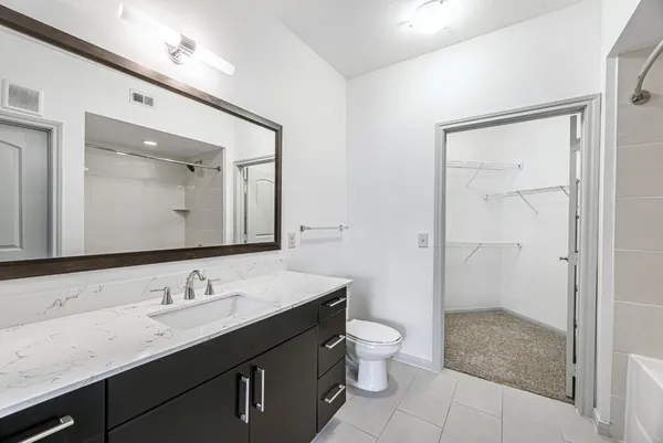 a bathroom with a granite countertop sink toilet a mirror a vanity and shower