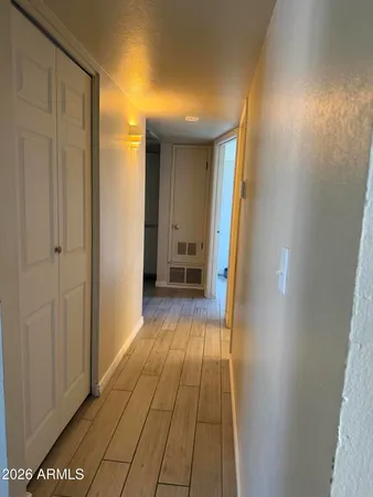 a view of a hallway with wooden floor and a bathroom