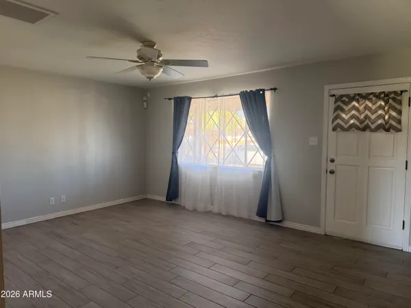 an empty room with wooden floor fan and windows