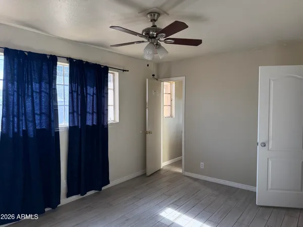 an empty room with wooden floor closet and windows