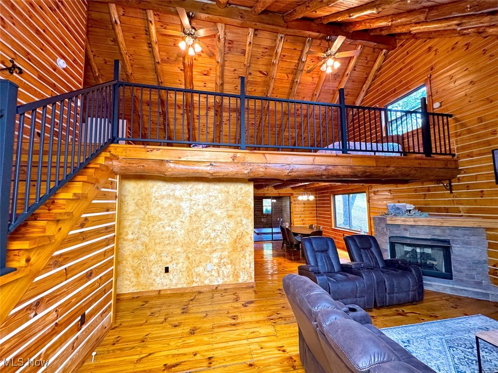 18063 Sligo Road Freeport, OH 43973 - Photo 32 of 50 Living room featuring high vaulted ceiling, wooden walls, hardwood / wood-style flooring, a wood ceiling with exposed beams, and a fireplace