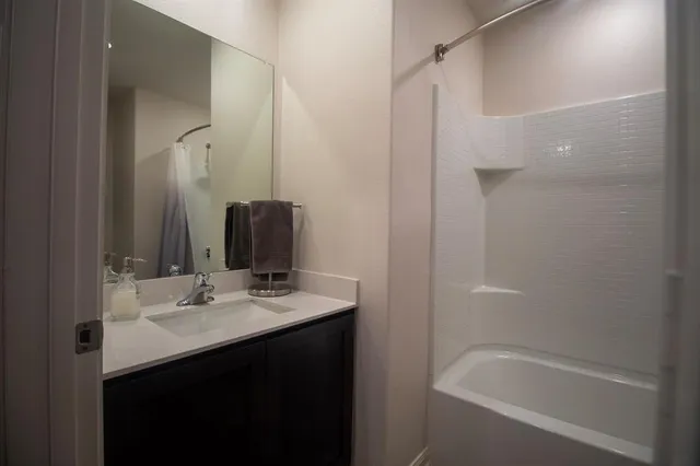 a bathroom with a bathtub sink vanity and mirror