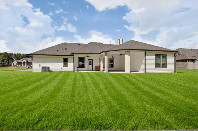 a view of a house with a big yard potted plants and large tree
