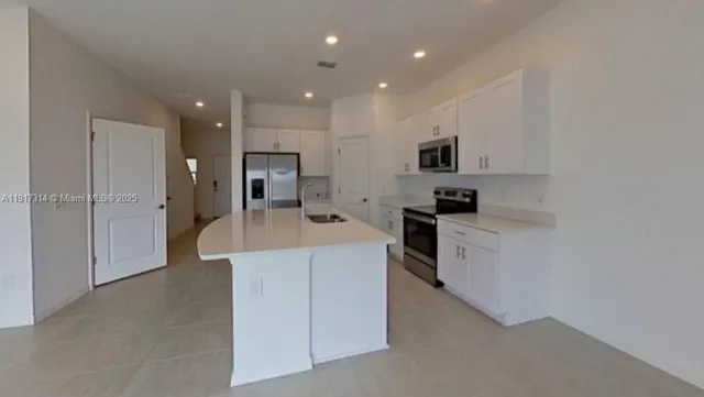 a large kitchen with kitchen island a sink stainless steel appliances and cabinets