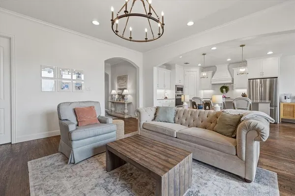 a living room with furniture kitchen view and a chandelier