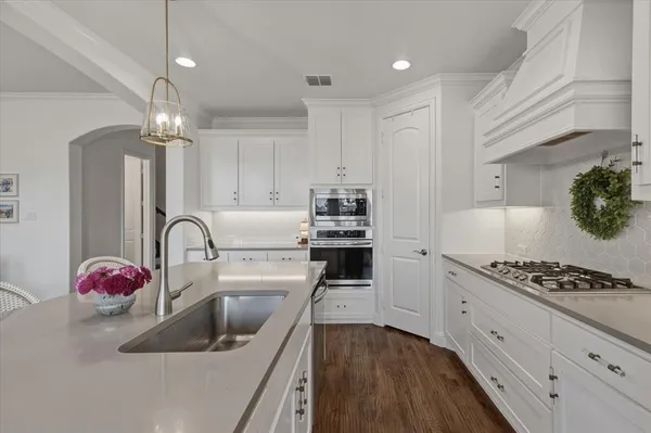 a kitchen with granite countertop a sink stainless steel appliances and cabinets