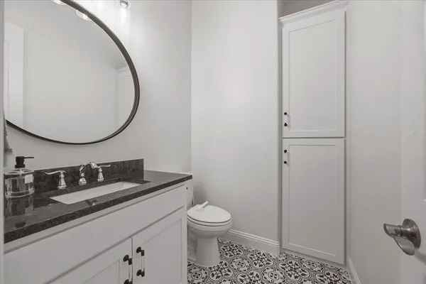 a bathroom with a granite countertop sink a toilet and a mirror
