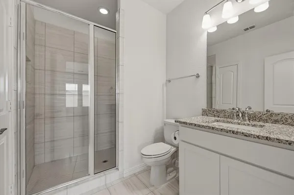 a bathroom with a granite countertop sink a toilet and shower