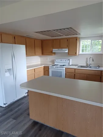 a kitchen with stainless steel appliances a sink a stove a refrigerator a center island and cabinets