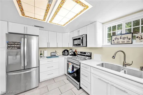 a kitchen with stainless steel appliances granite countertop a refrigerator sink and white cabinets