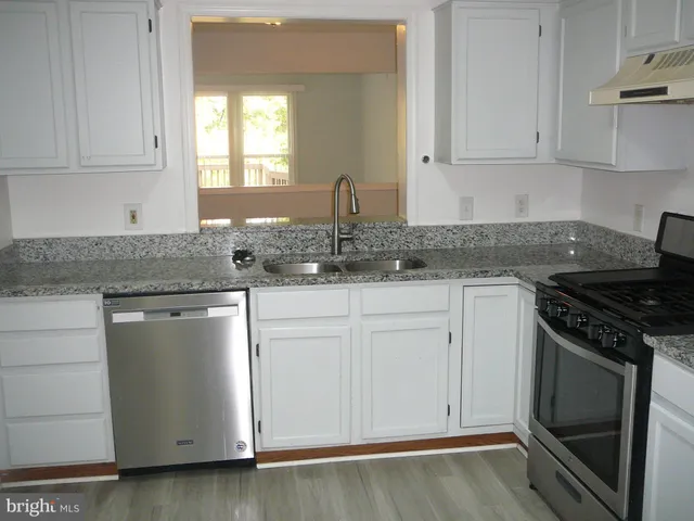 a kitchen with granite countertop white cabinets and a stove