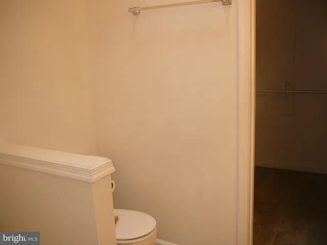 a white toilet sitting next to a white wall