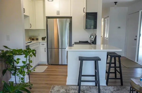 a kitchen with a refrigerator a oven a counter space and wooden floor