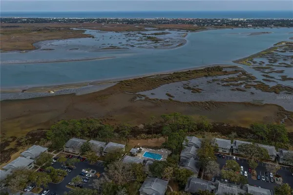 an aerial view of ocean and residential houses with outdoor space