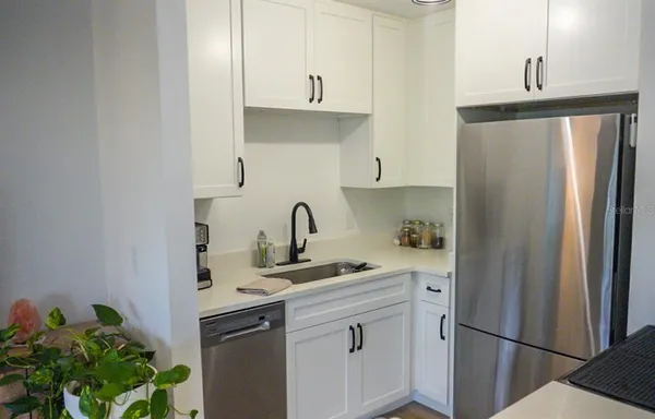a kitchen with stainless steel appliances granite countertop a refrigerator sink and white cabinets