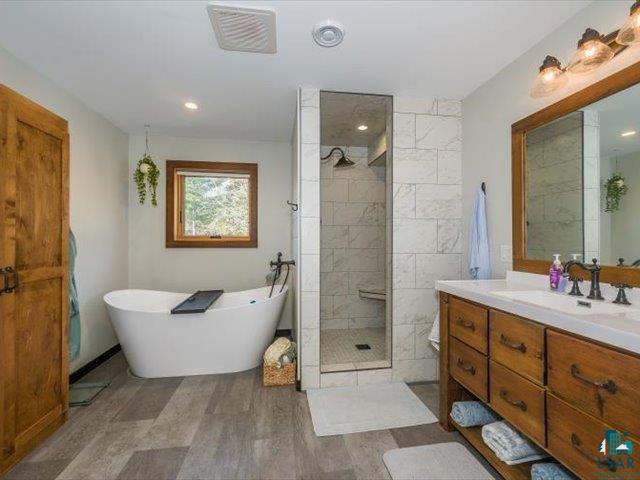 5508 Nordling Road Duluth, MN 55804 - Photo 18 of 58 Full bath featuring vanity, a freestanding bath, a tile shower, and dark wood-style floors