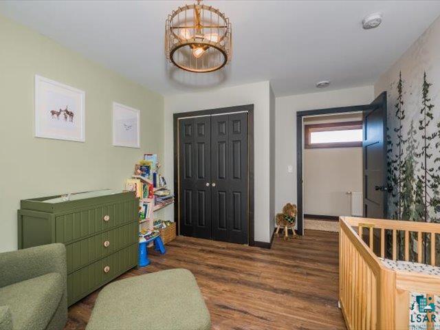 5508 Nordling Road Duluth, MN 55804 - Photo 26 of 58 Bedroom featuring a crib, a closet, dark wood-style floors, radiator, and a chandelier