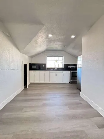a view of a kitchen with a sink and dishwasher a stove top oven with wooden floor