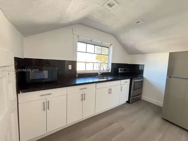 a kitchen with granite countertop white cabinets and stainless steel appliances