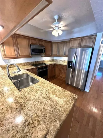 a kitchen with stainless steel appliances granite countertop a sink a stove cabinets and wooden floor