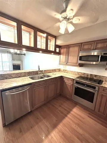 a view of a kitchen with granite countertop a refrigerator a stove top oven and a wooden floors
