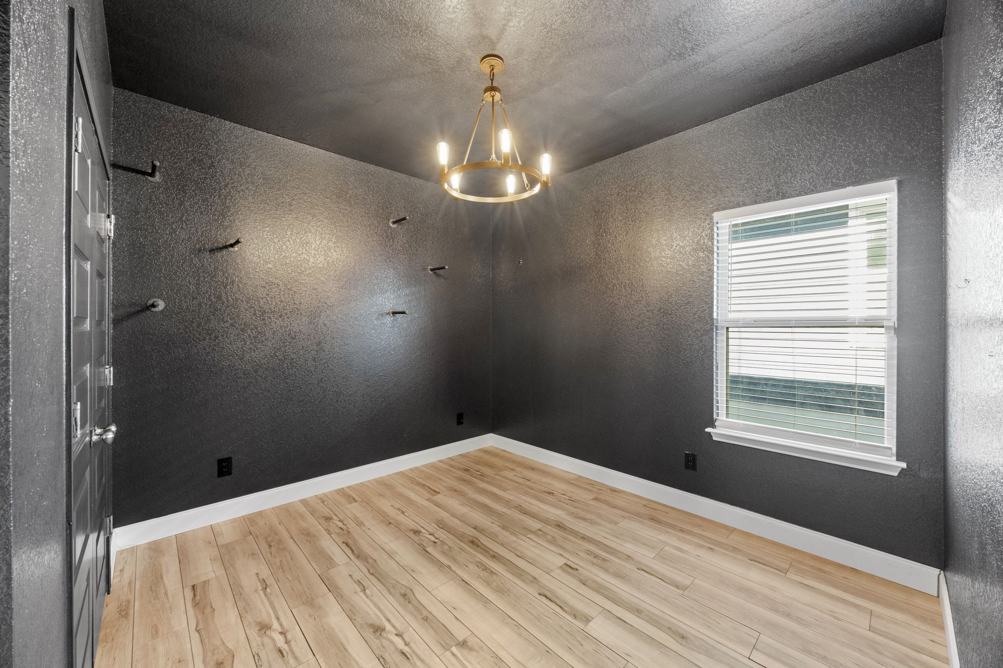 225 Unforgiven Lane Jarrell, TX 76537 - Photo 20 of 30 Spare room featuring light wood-type flooring, a chandelier, a textured wall, and a textured ceiling
