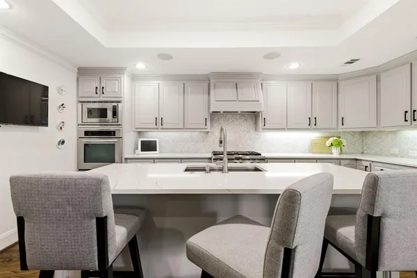 a kitchen with stainless steel appliances granite countertop a table chairs microwave and sink