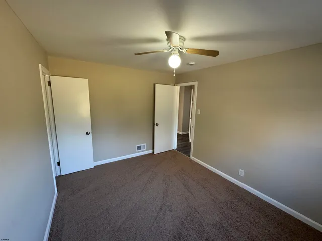 an empty room with closet and a chandelier fan