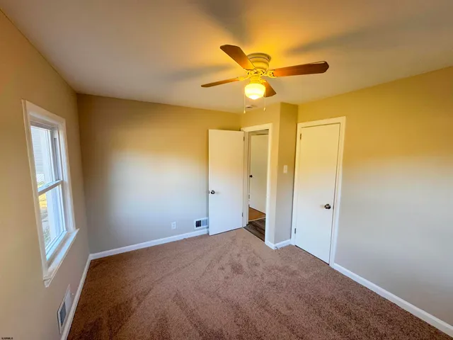 a view of a big room with windows and chandelier fan