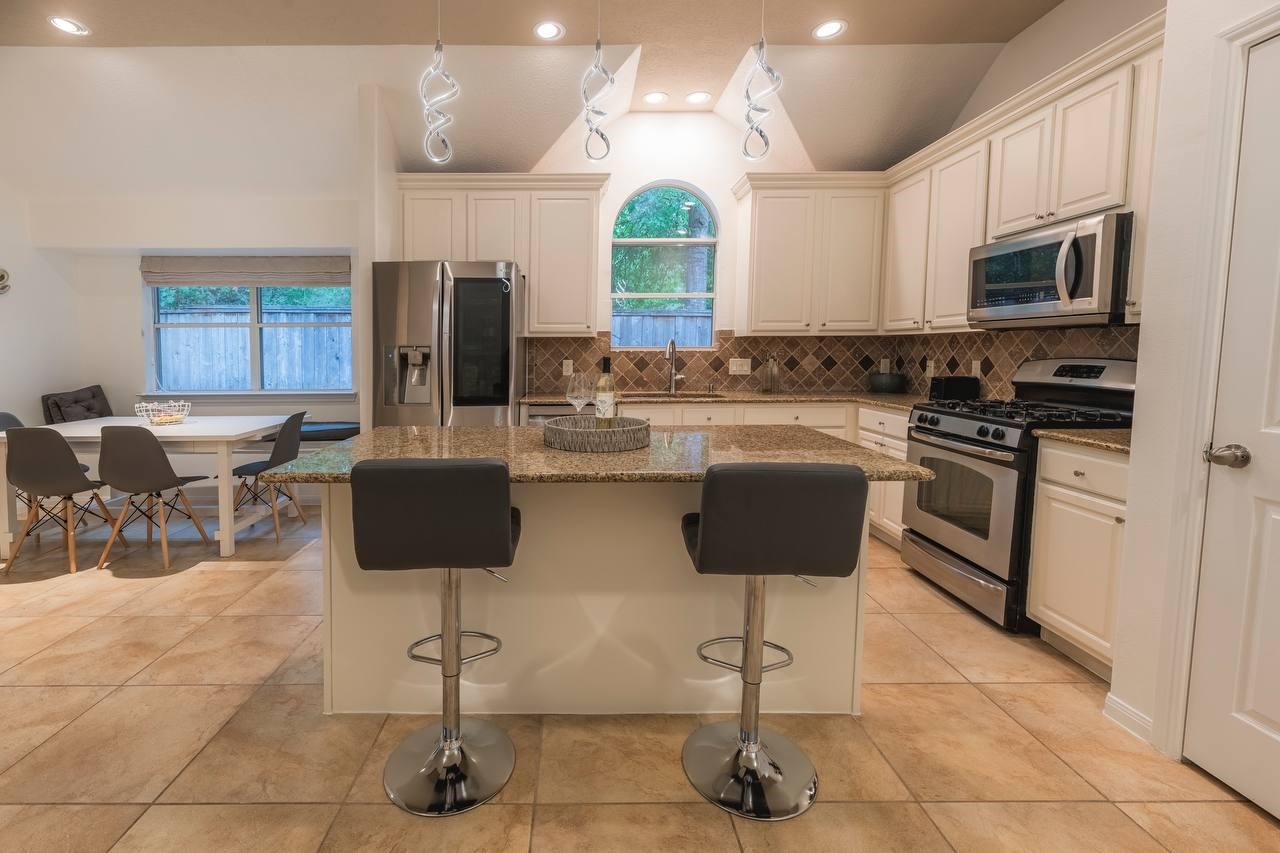 6 Avenswood Place Spring, TX 77382 - Photo 9 of 22 a kitchen with stainless steel appliances a stove a sink island and chairs in it