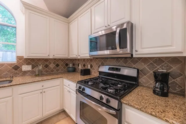 a kitchen with stainless steel appliances granite countertop white cabinets and a stove a oven with granite countertops