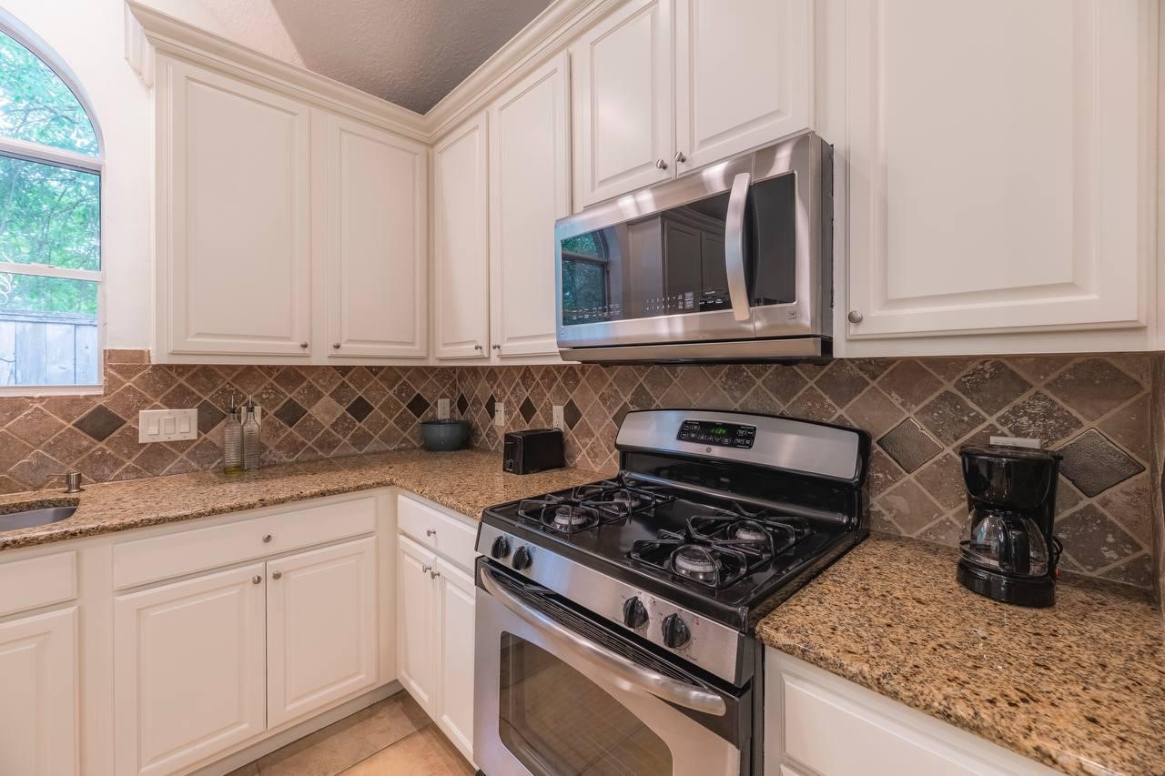6 Avenswood Place Spring, TX 77382 - Photo 10 of 22 a kitchen with stainless steel appliances granite countertop white cabinets and a stove a oven with granite countertops