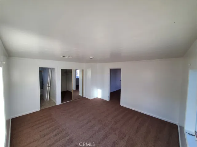 a view of an empty room with window and a kitchen